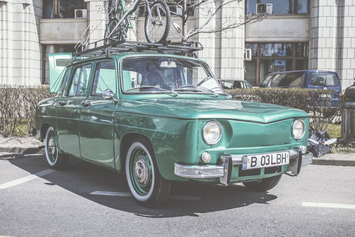 Vintage classic sedan with roof bicycle carrier and round headlights.