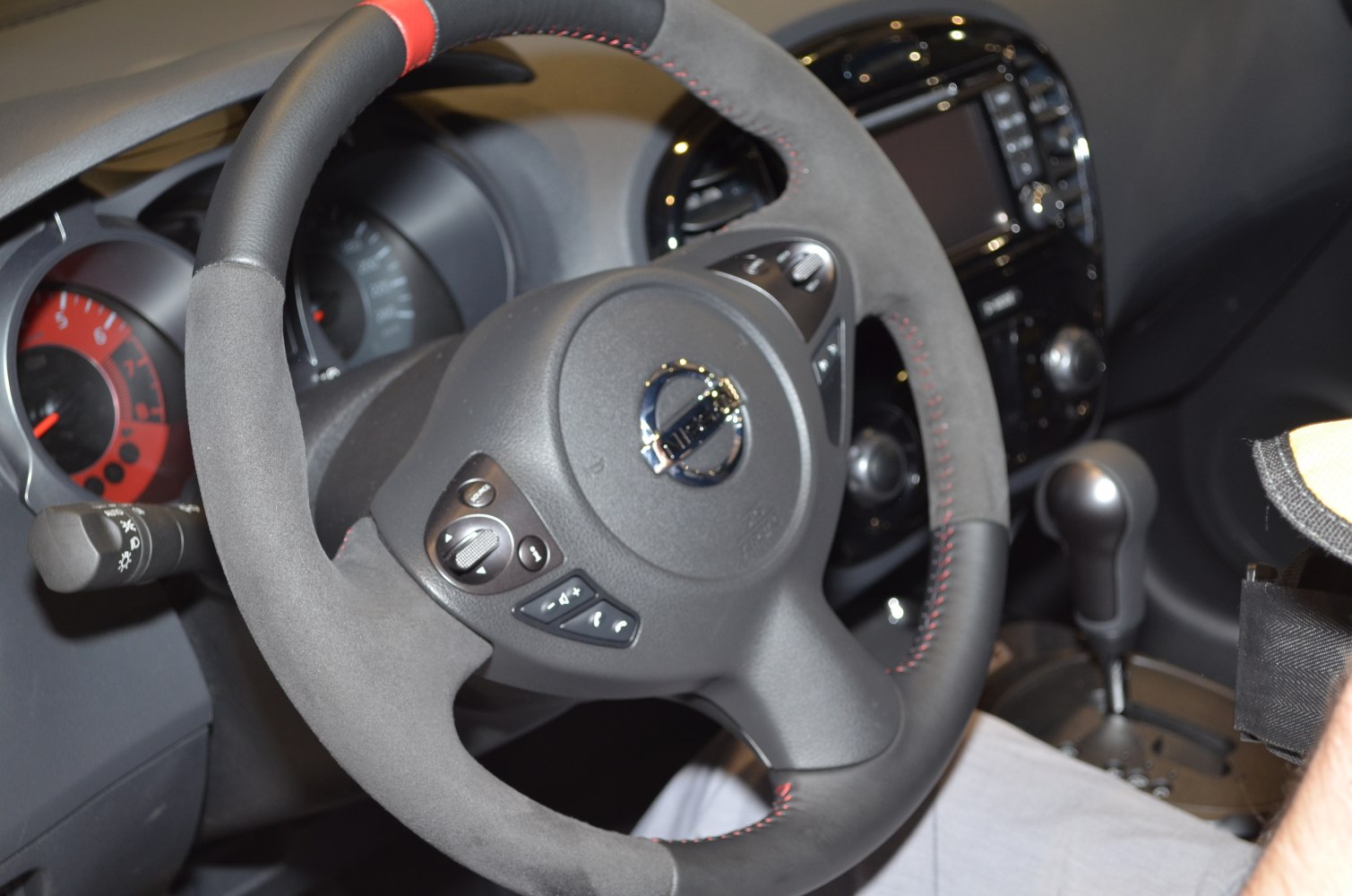 Steering wheel with control buttons and dashboard including speedometer and gear shift lever.