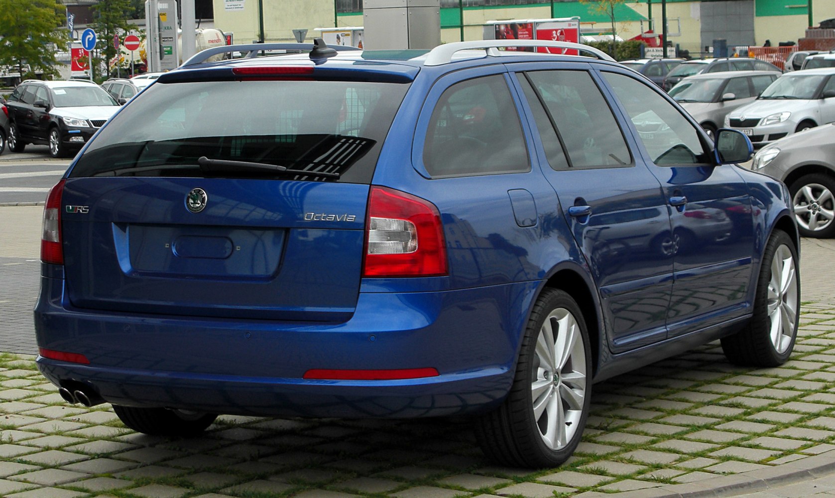 Blue estate car showing rear and side profile with tail lights and dual exhaust