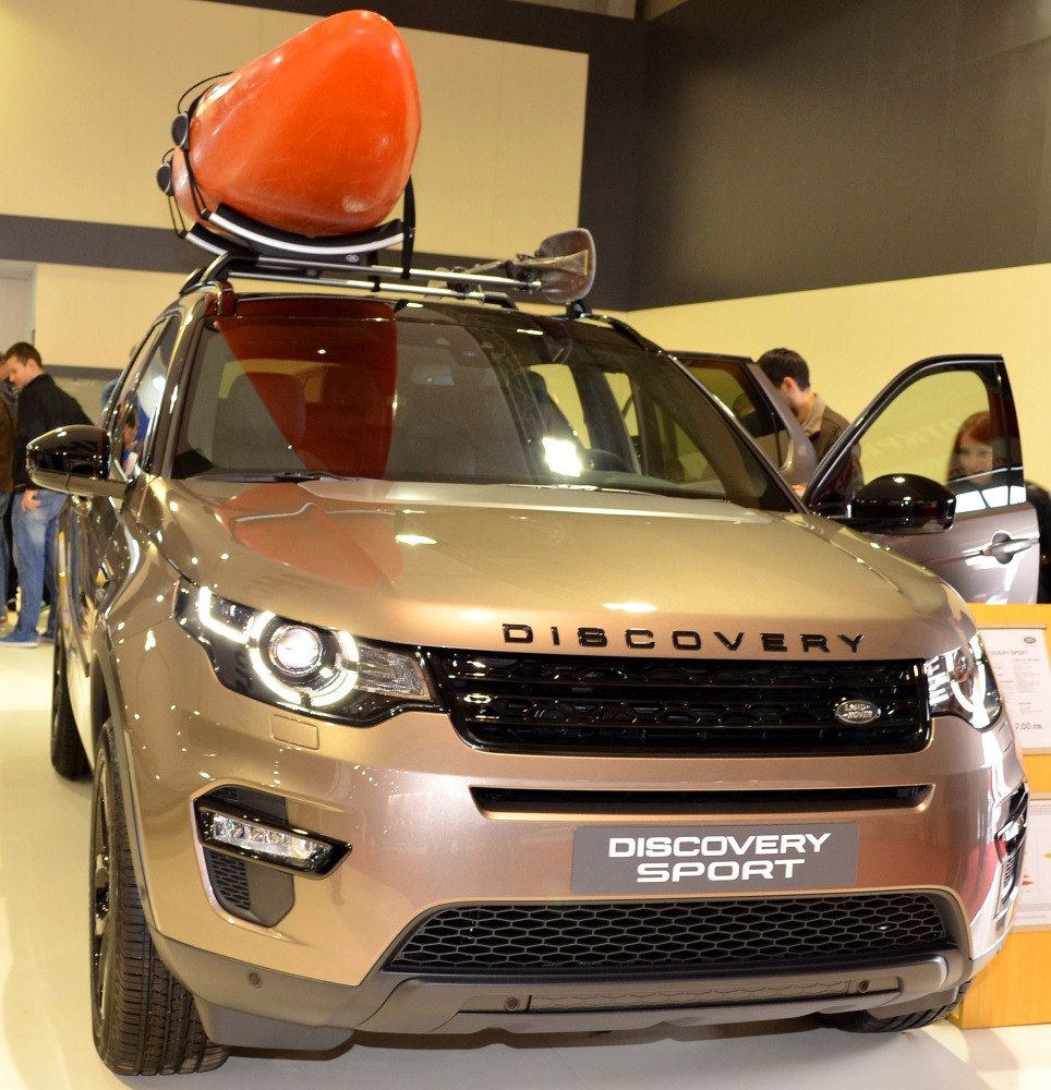 SUV with mounted roof rack and orange kayak