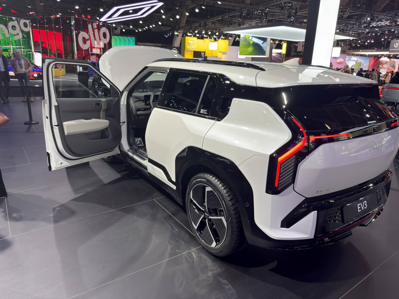 Rear of electric SUV with open front door and bold taillights in black-white color contrast.