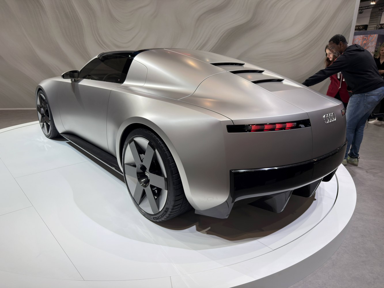 Rear view of sleek, aerodynamic concept car with futuristic design and unique wheels.