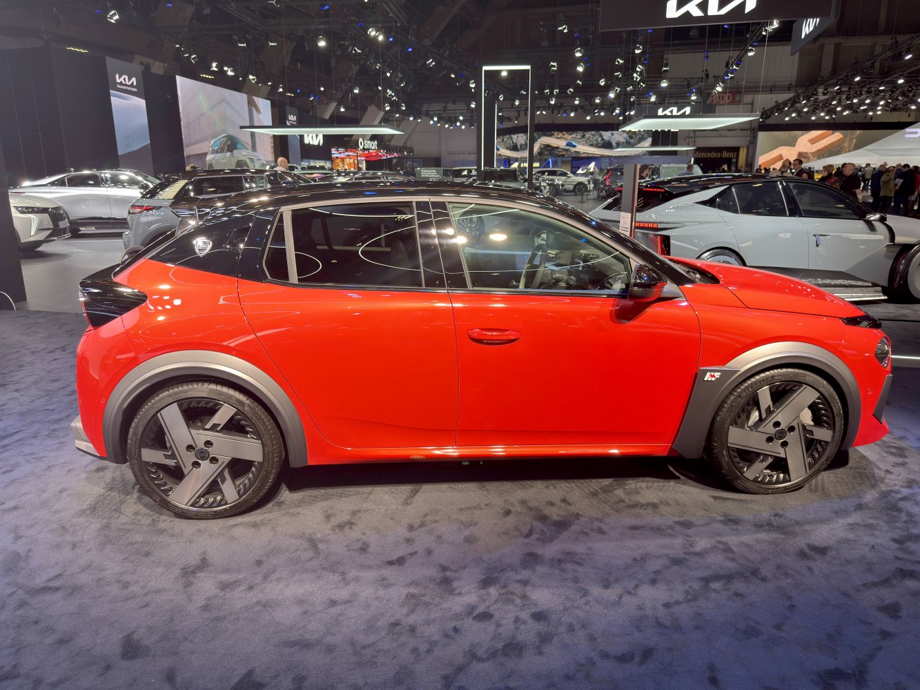 Side profile of a red urban compact hatchback with black roof and modern alloy wheels