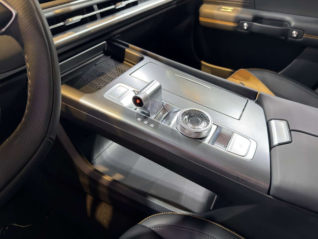 Modern gear shift and sleek center console with control dial and electronic parking brake