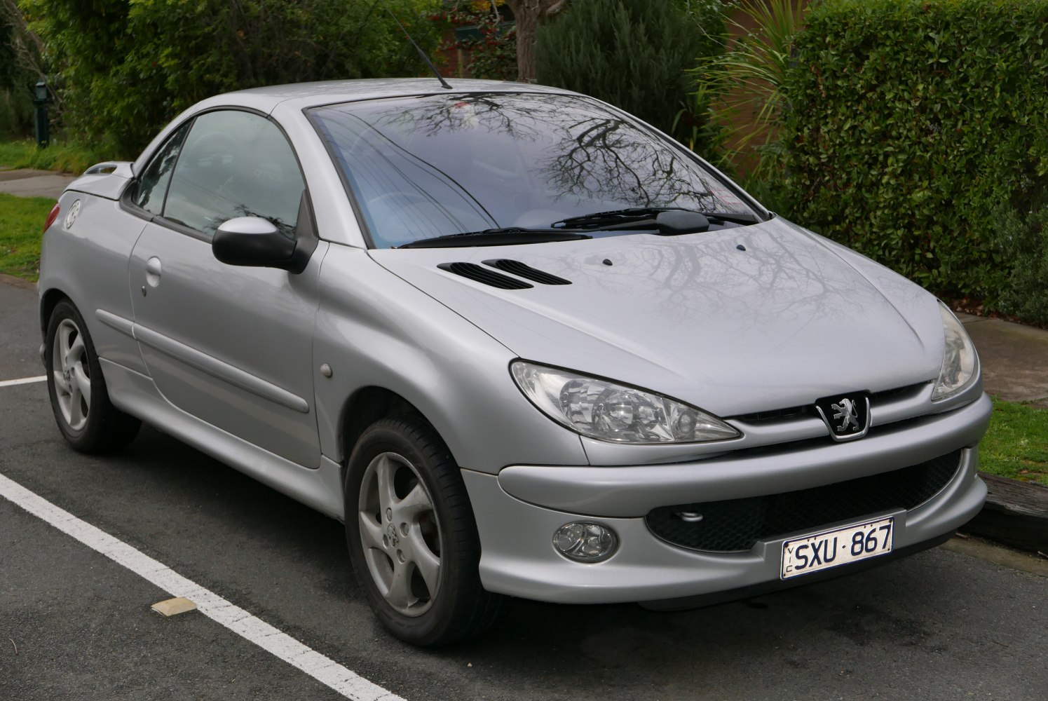 Silver hardtop convertible with sporty front view and distinctive Peugeot headlights