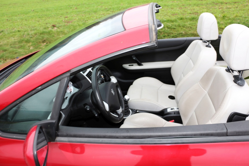 Convertible car interior with retractable roof and white leather seats