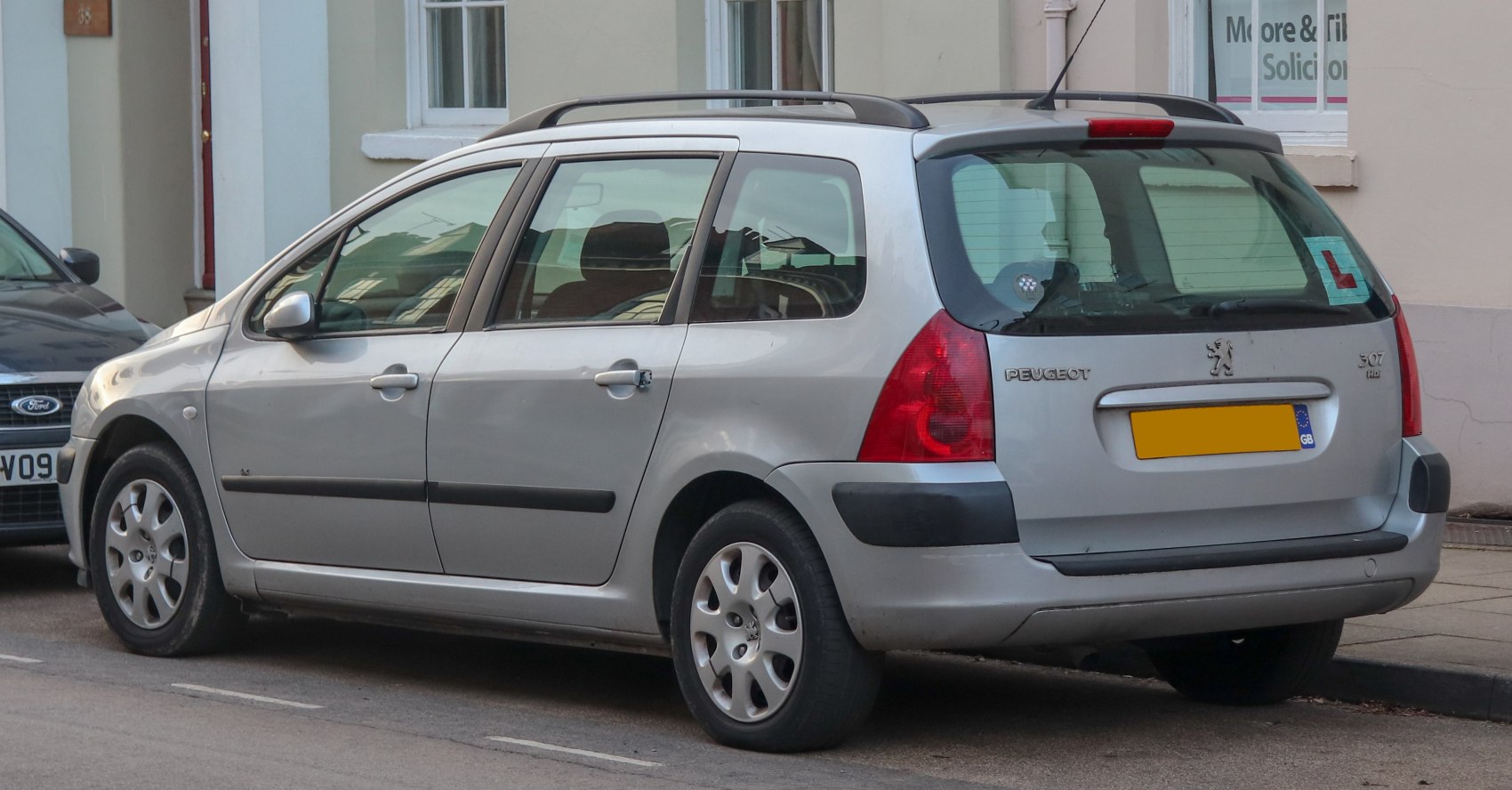 Silver estate car with rear side view and visible roof rails.