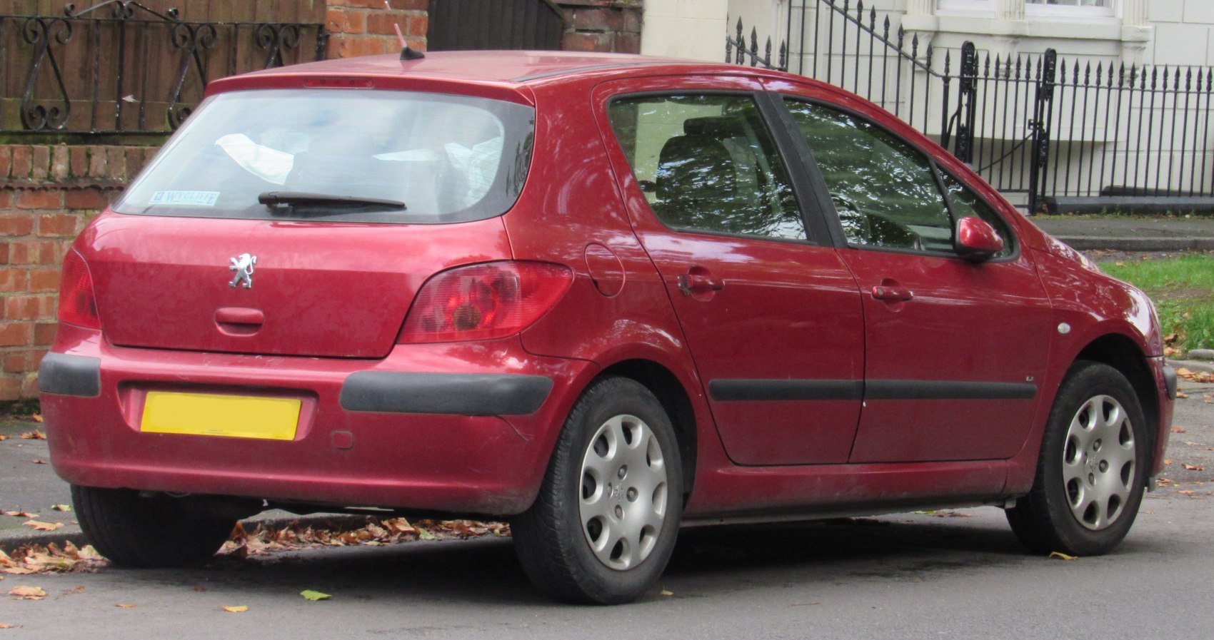 Red compact hatchback rear view with distinctive tail lights and rear wiper