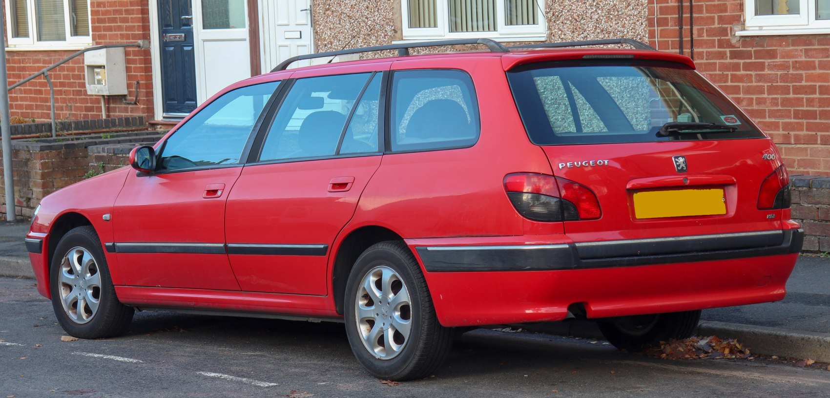 Rear side angle of red station wagon with roof rails and rear lights.