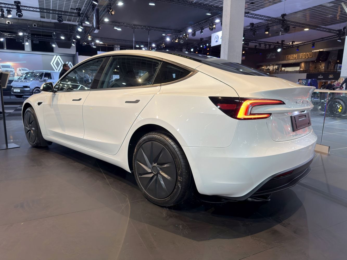 Rear-side view of a white electric sedan with LED taillights and aerodynamic wheels