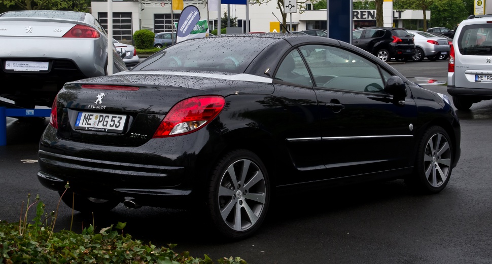 Rear and side view of black convertible coupe with alloy wheels and raindrops
