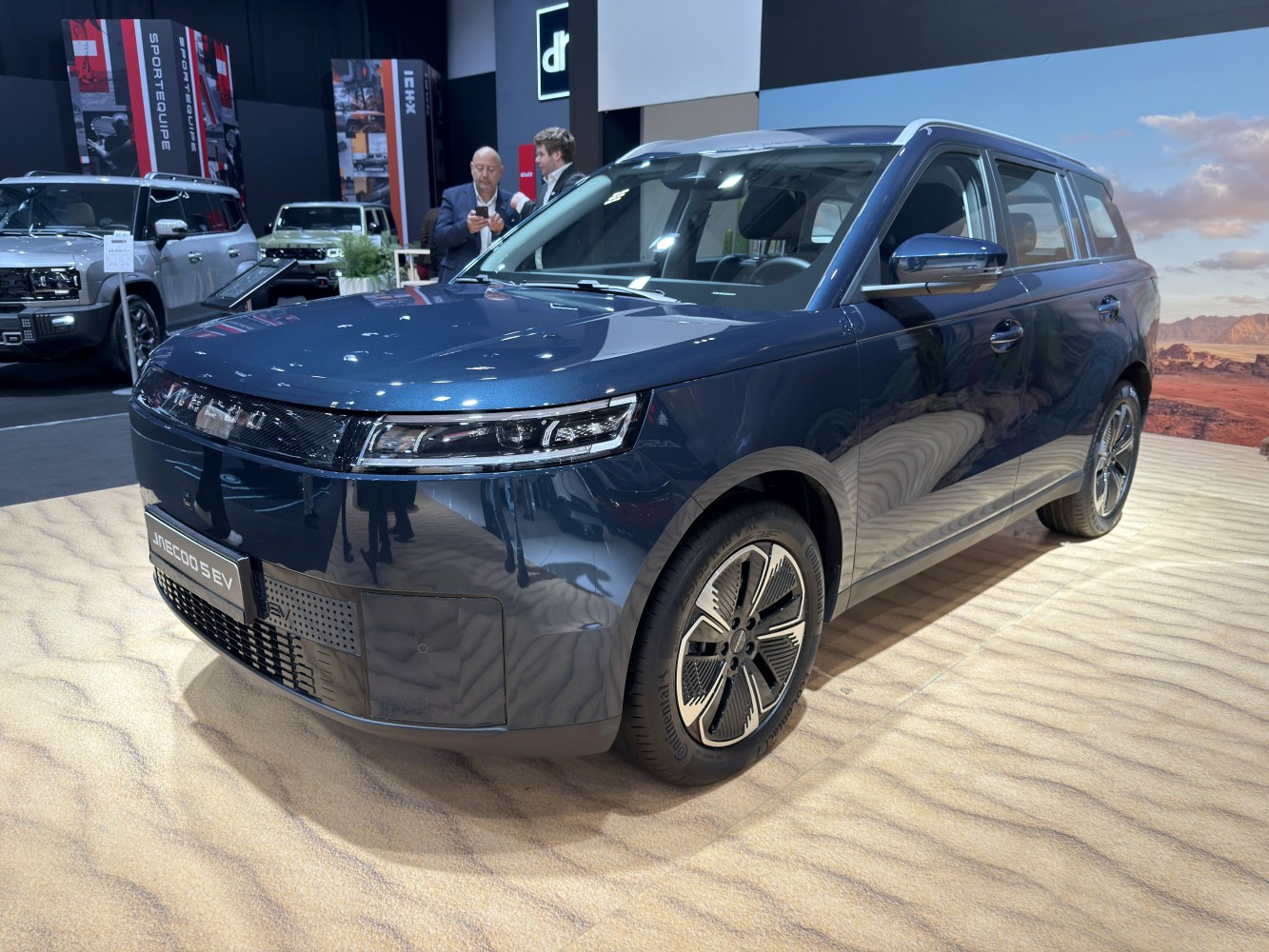 Front and side view of a blue electric SUV with modern headlights and aerodynamic wheels.