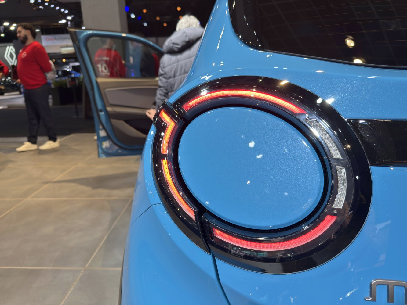 Circular LED rear light close-up on blue car body.
