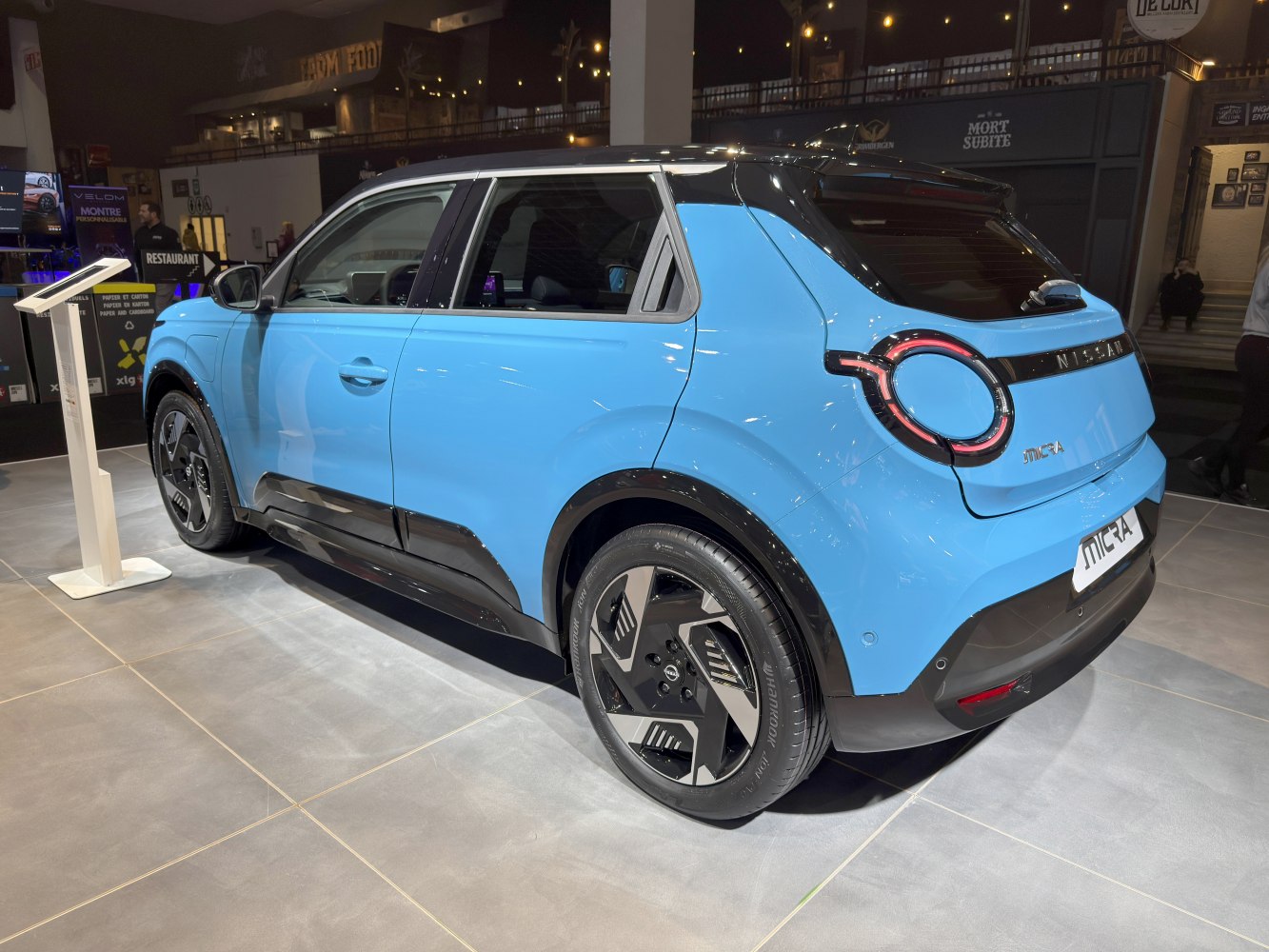 Rear side view showing round taillights and aerodynamic blue hatchback