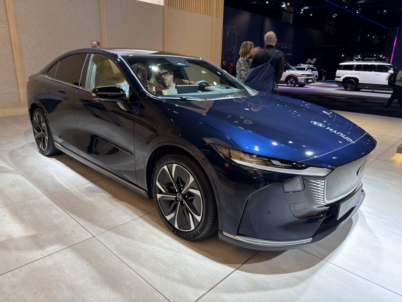 Front side view of an electric sedan with LED headlights and sleek wheels