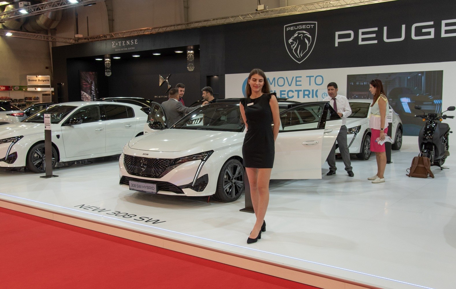 White Peugeot 308 SW III hybrid front view with open door and promotional model.