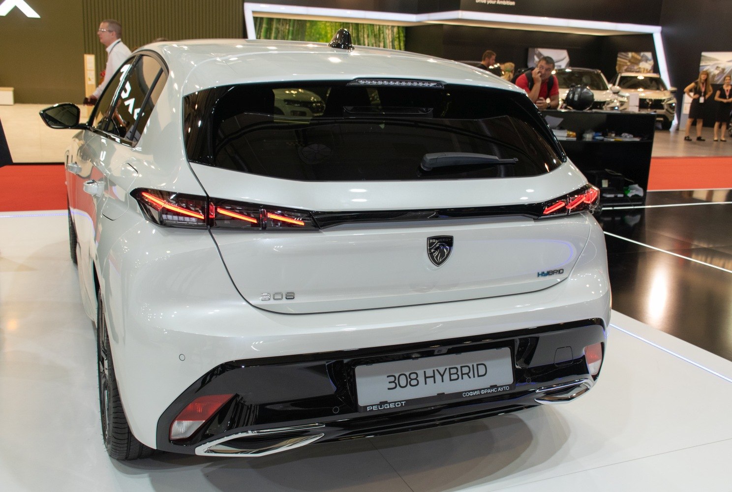 Rear view of a white hybrid hatchback with modern LED taillights.