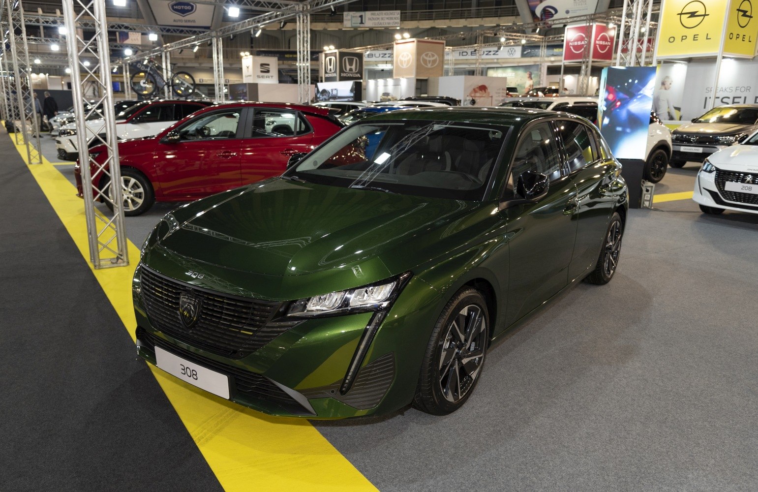 Front and side view of dark green hatchback with sleek headlights and alloy wheels.