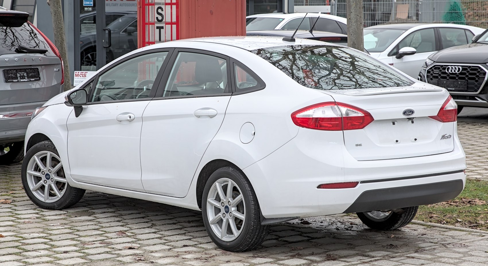 White sedan showing rear and side view with alloy wheels