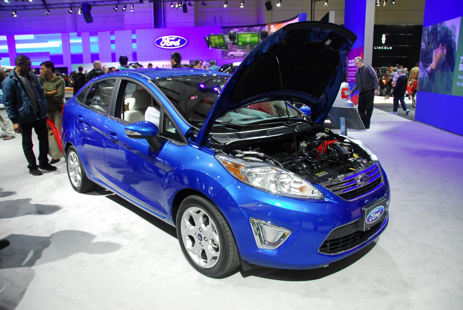 Blue compact sedan with open hood showing engine bay.
