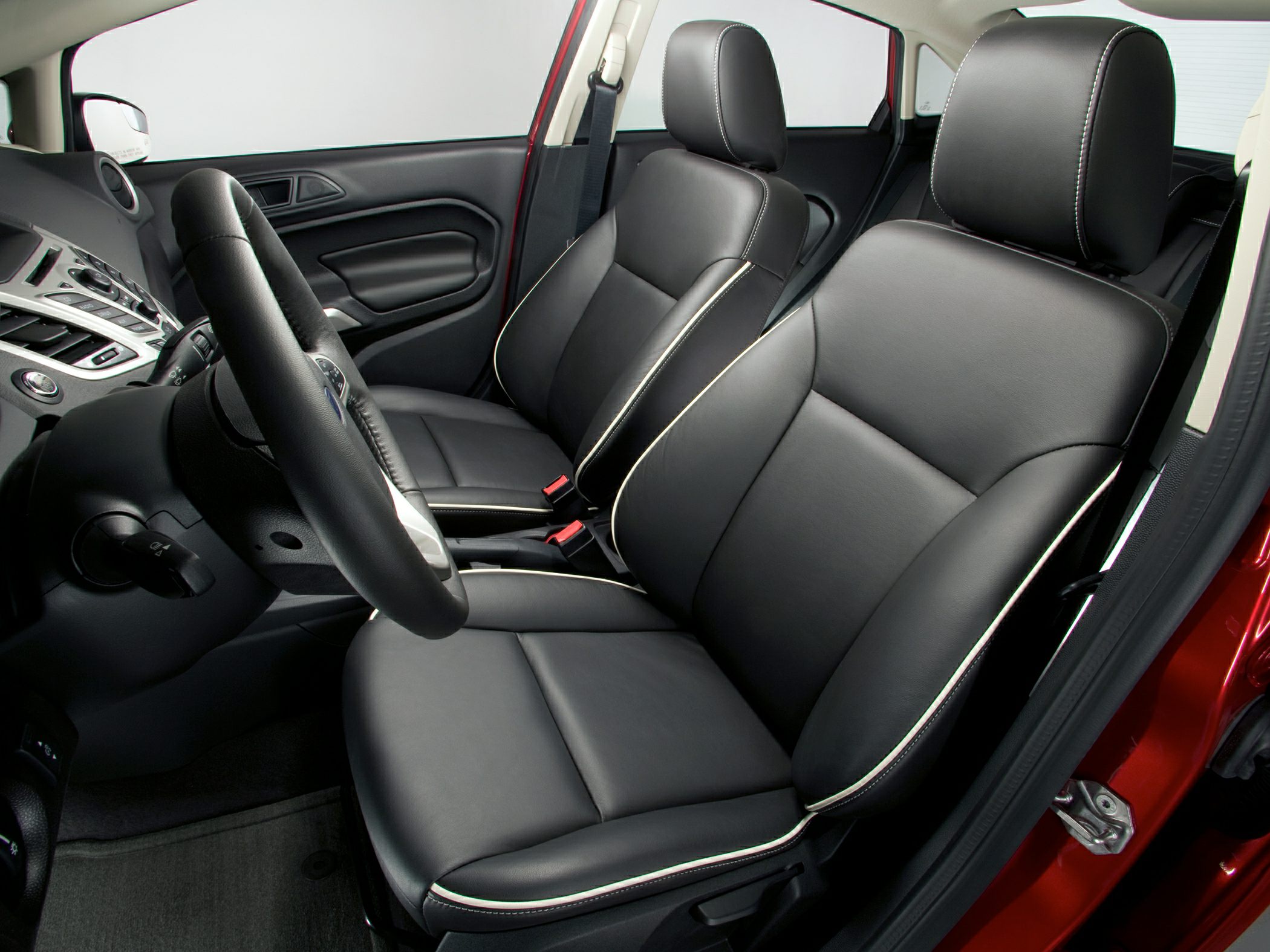 Black leather car seats with white stitching and a textured steering wheel.