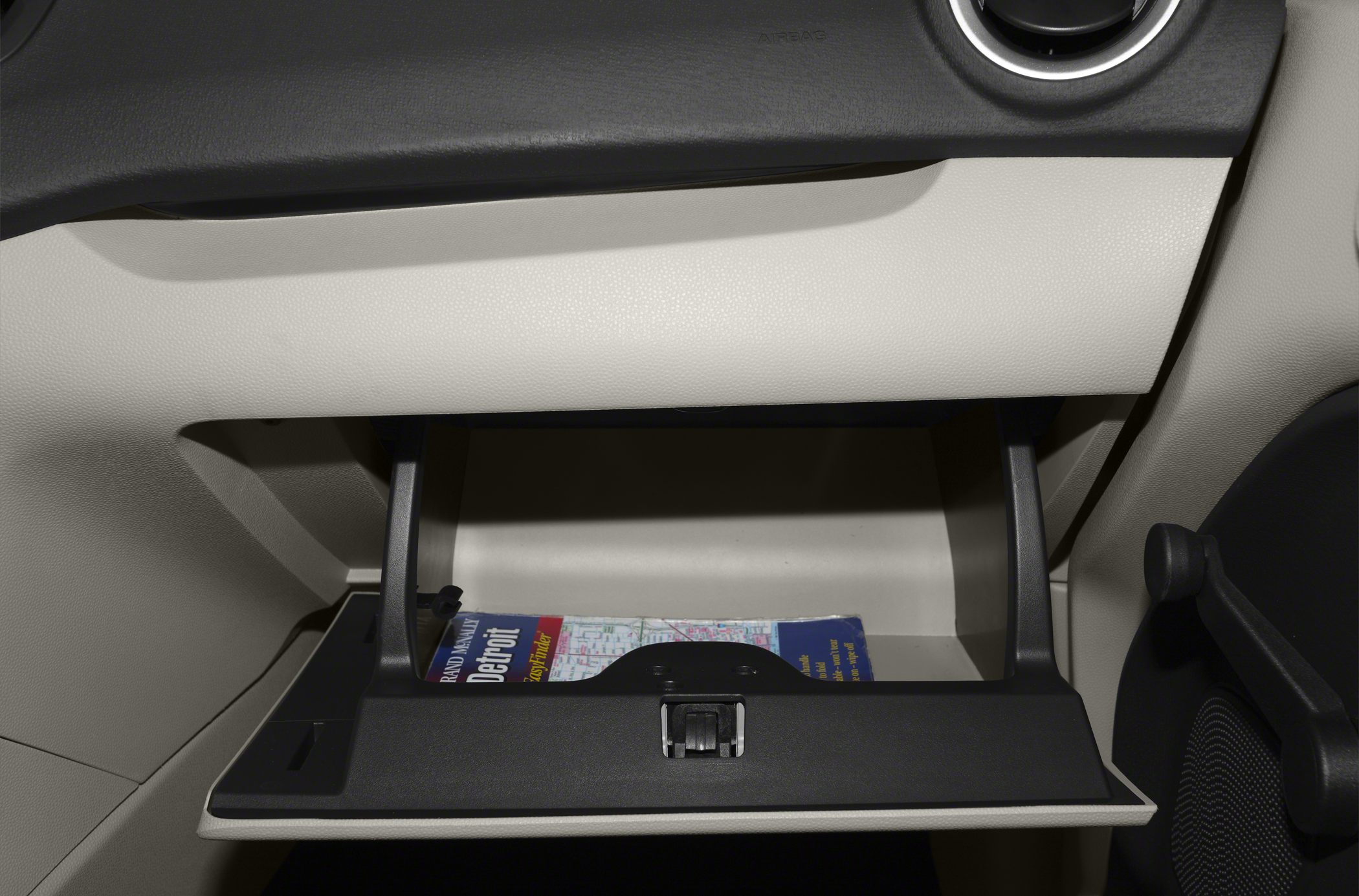 Open beige glove box with booklet inside in car interior