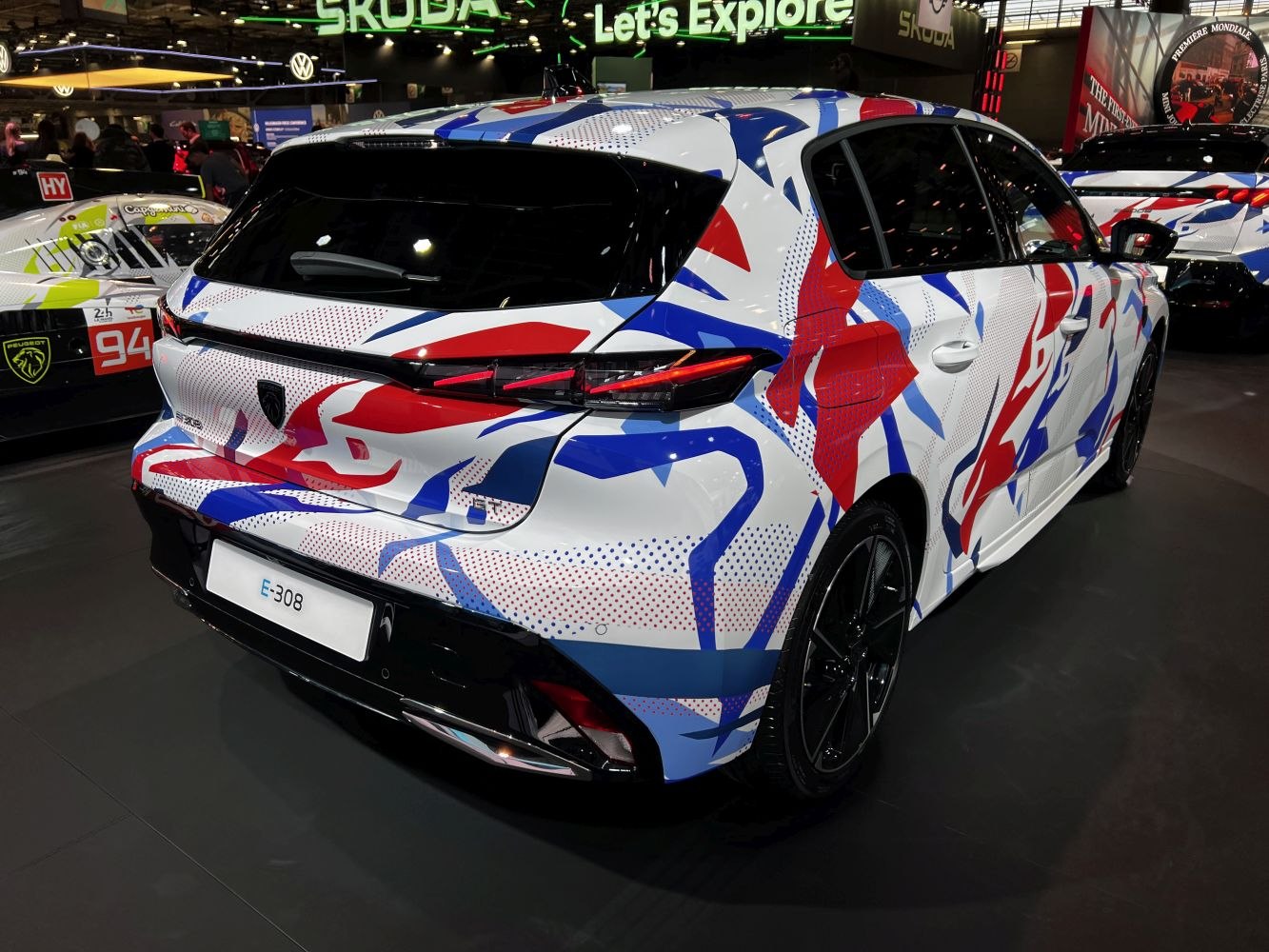 Rear three-quarter angle of hatchback with red, blue, and white graphic decal wrap