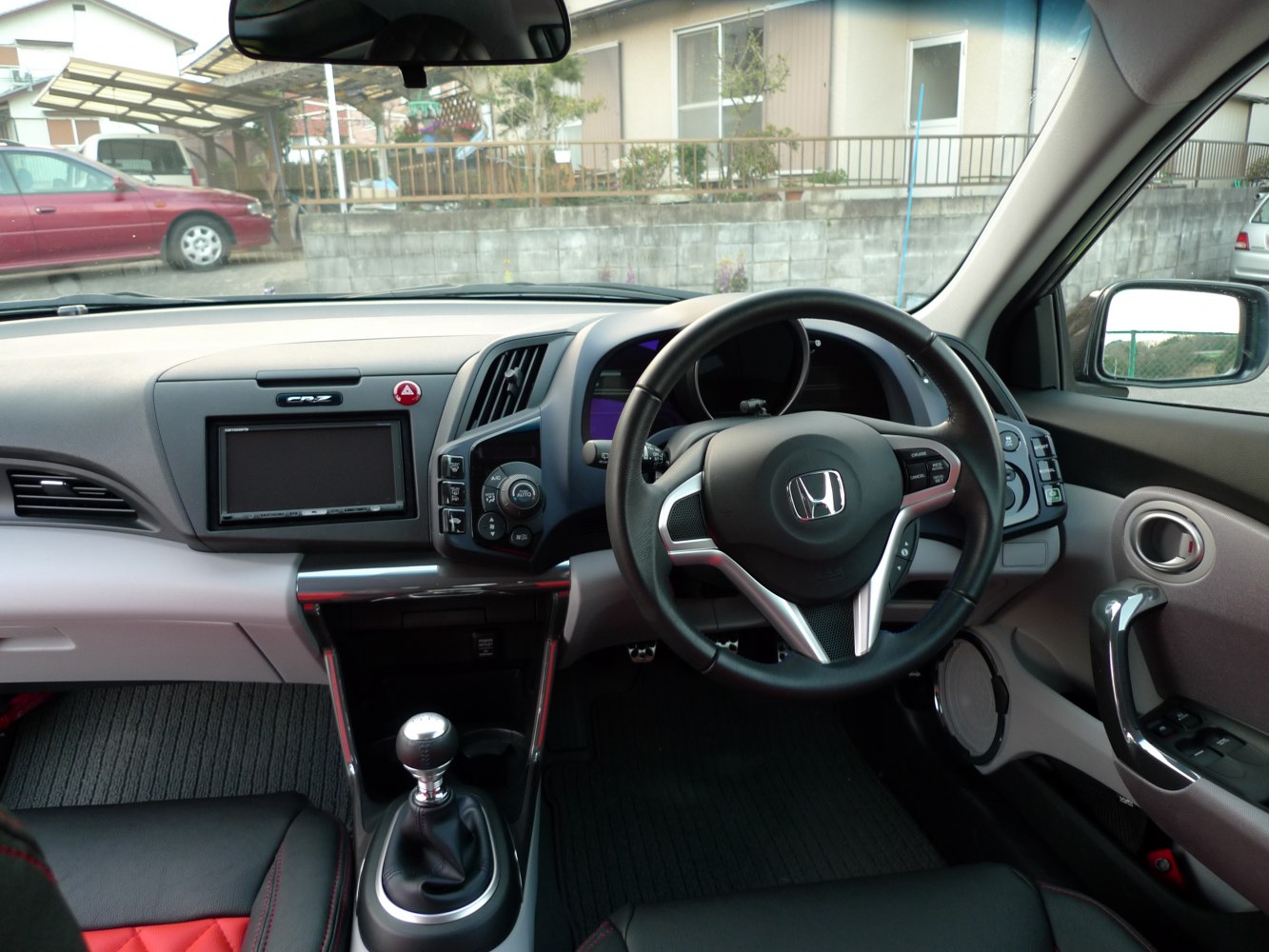 Manual gear shift and steering wheel controls in compact car interior