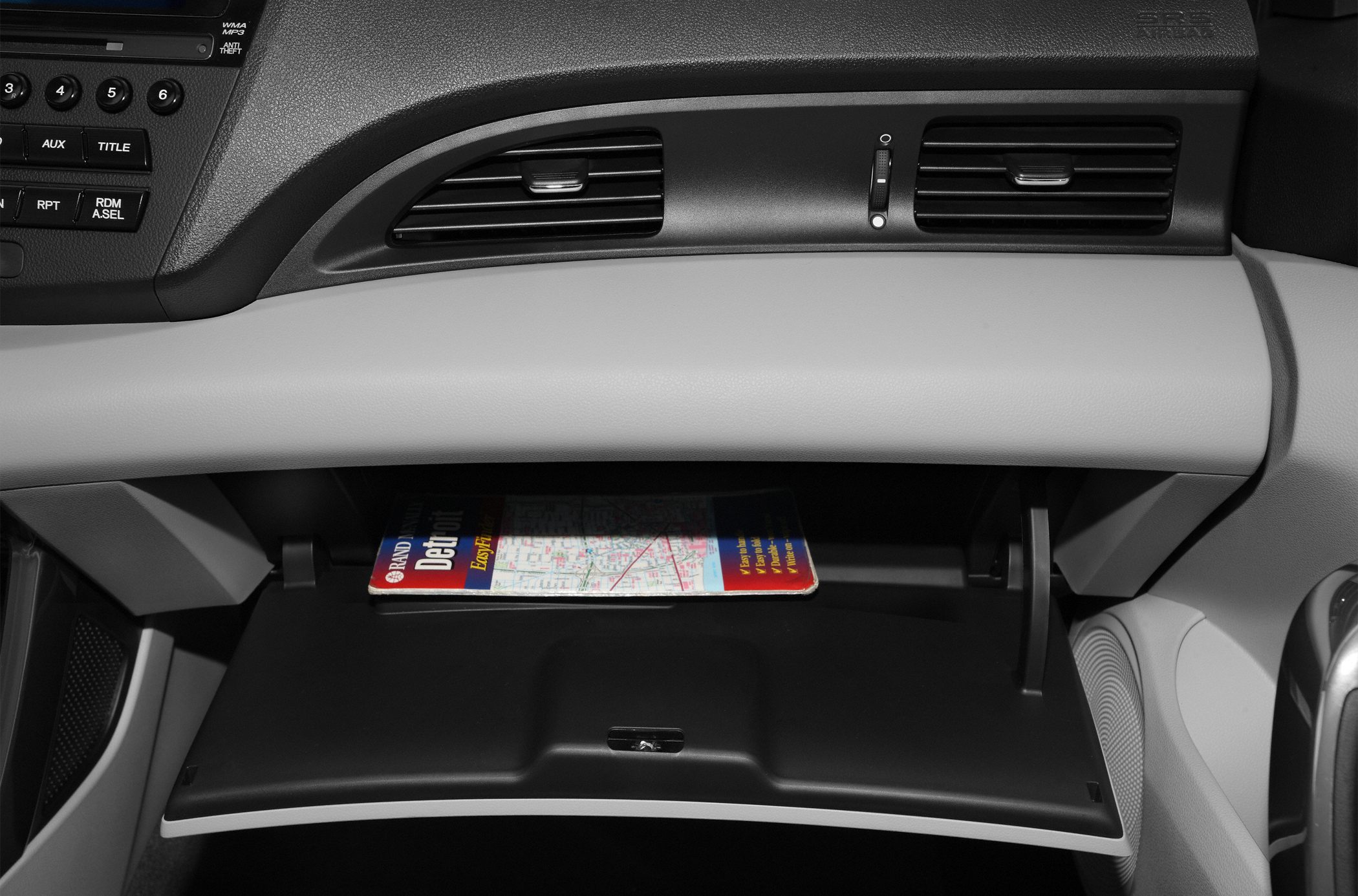 Open glove box and dashboard air vents with radio controls
