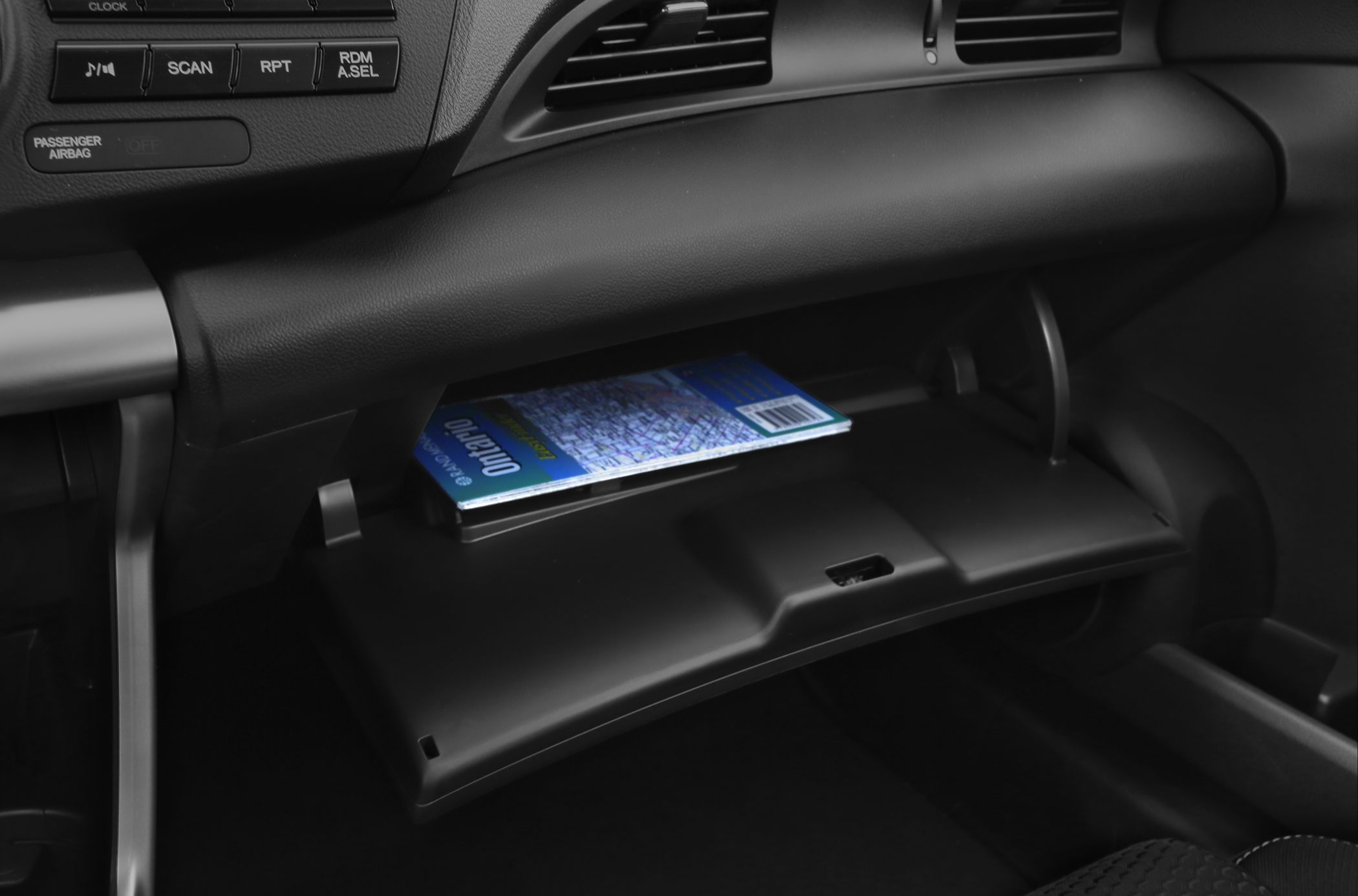 Open glove compartment with stored map in compact hybrid car interior
