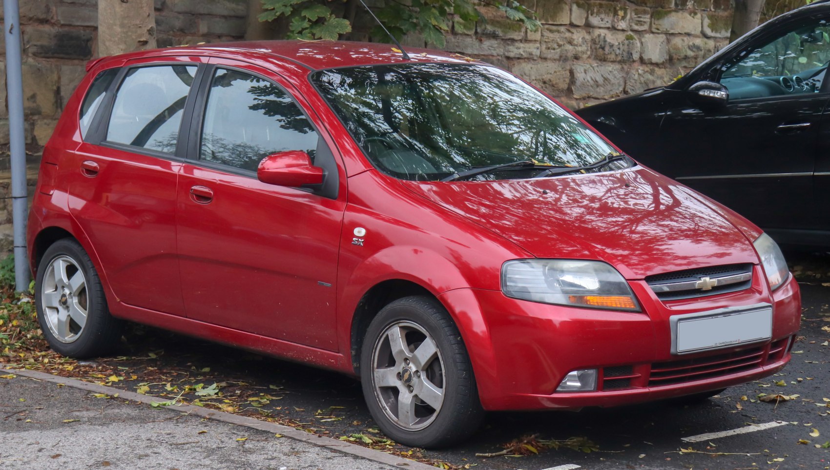 Red 5-door compact hatchback with alloy wheels parked on street