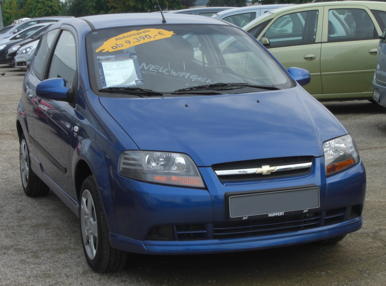 Front view of blue 3-door hatchback with headlights and grille