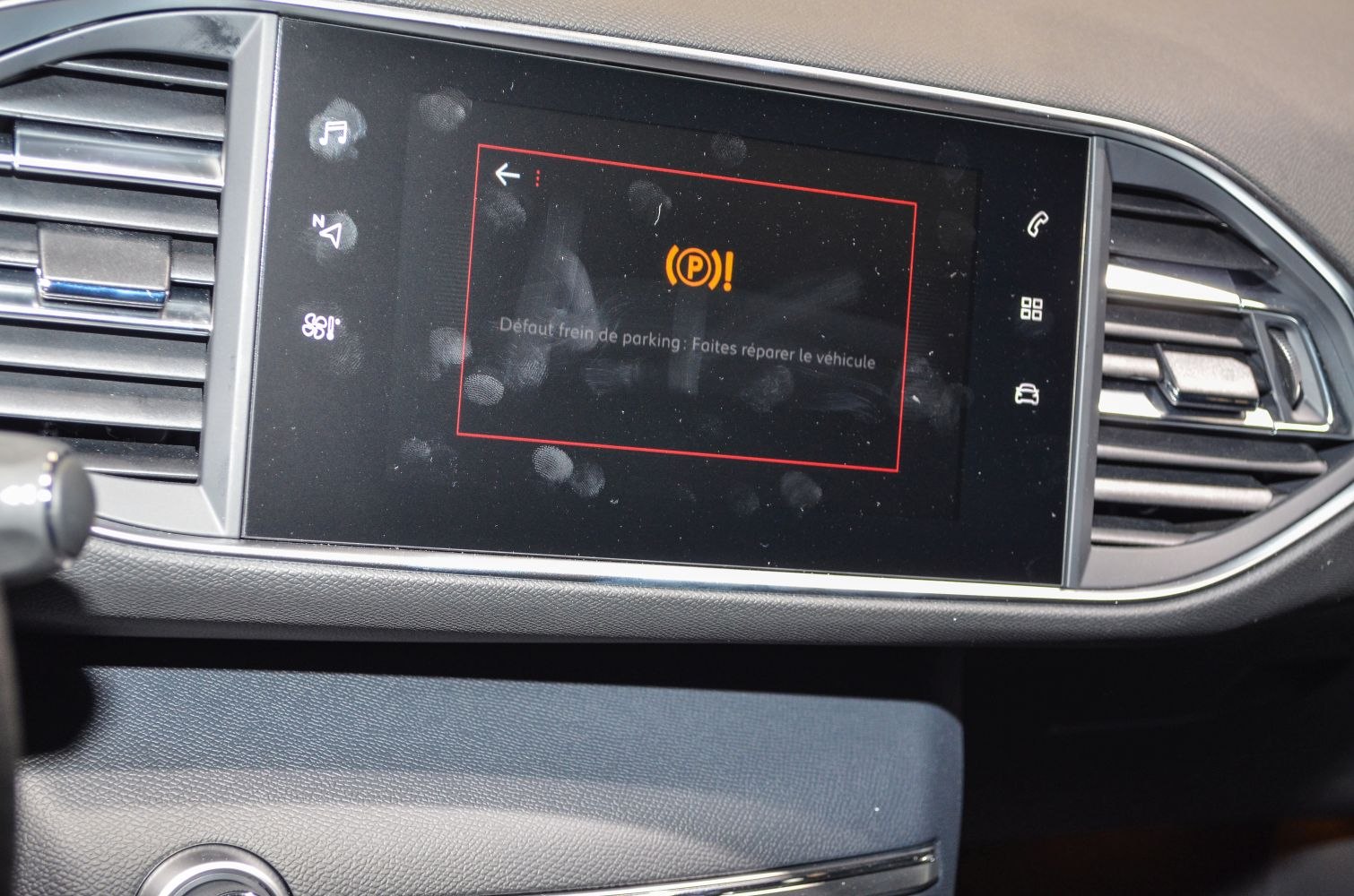 Infotainment screen displaying parking brake warning message in vehicle dashboard