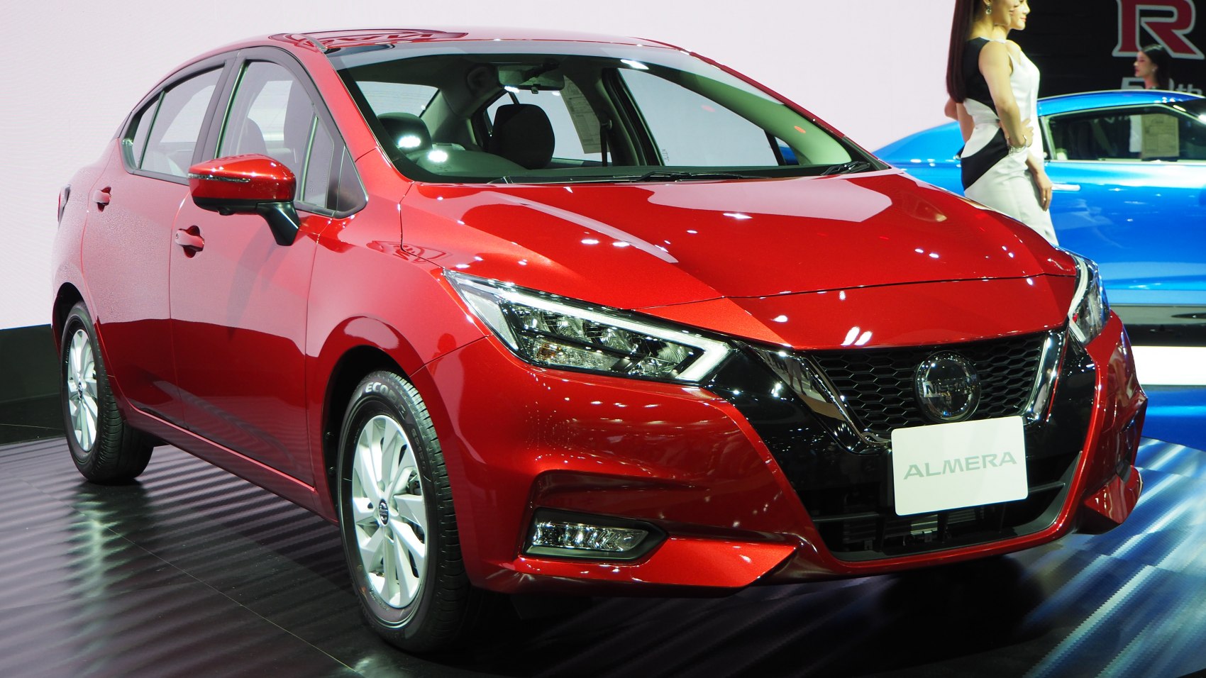 Red sedan with sharp LED headlights and black grille
