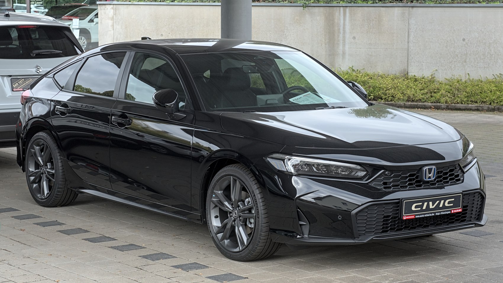 Front-side view of sleek black sedan with modern headlights and prominent grille
