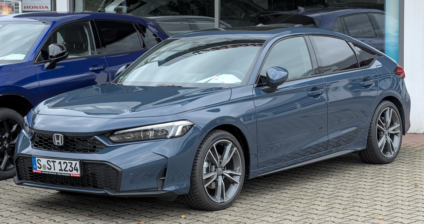 Front-side view with sleek headlights, honeycomb grille, and alloy wheels