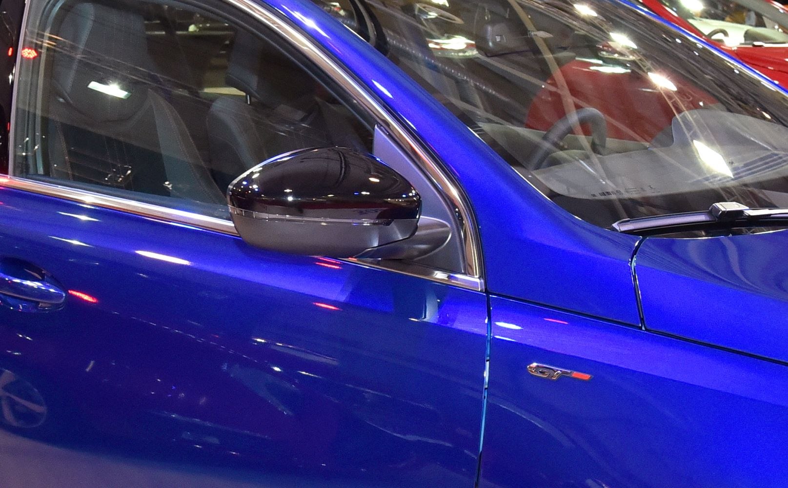 Close-up of black side mirror and GT badge on blue vehicle