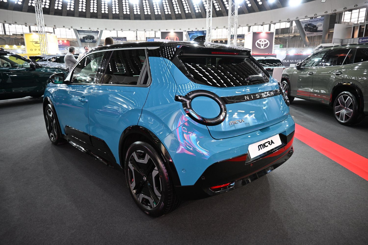 Rear view of a blue hatchback with distinctive round tail lights under showroom lights