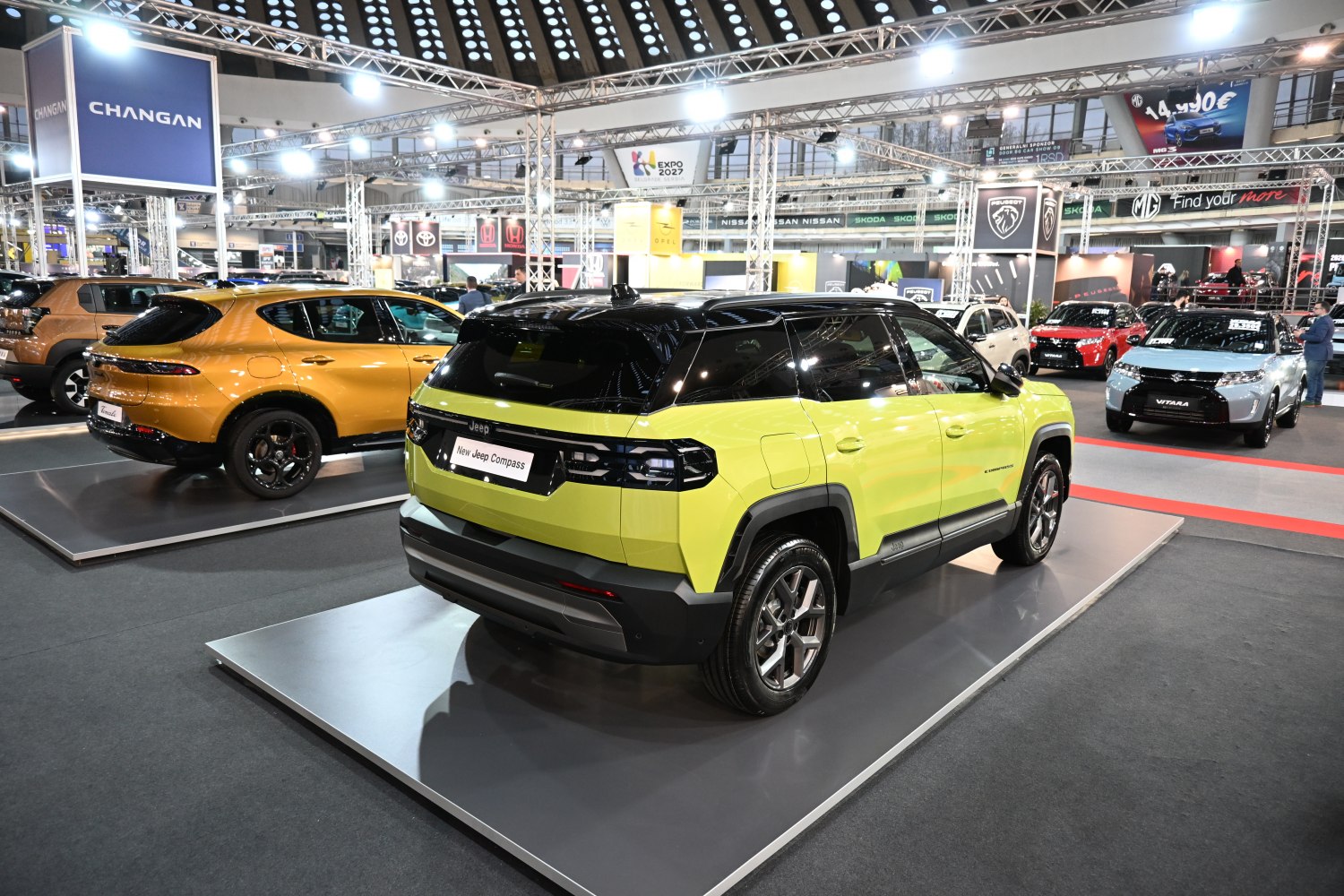 Rear-side view of yellow-black two-tone SUV at auto show