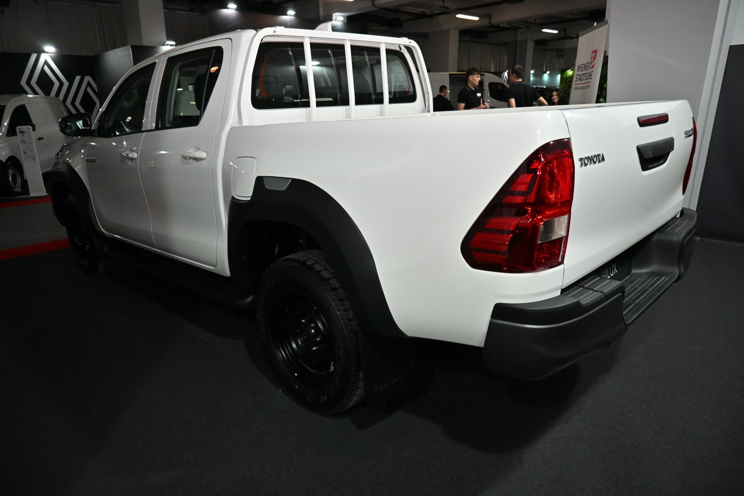 Side and rear view of a white pickup with black wheel arches and red taillights