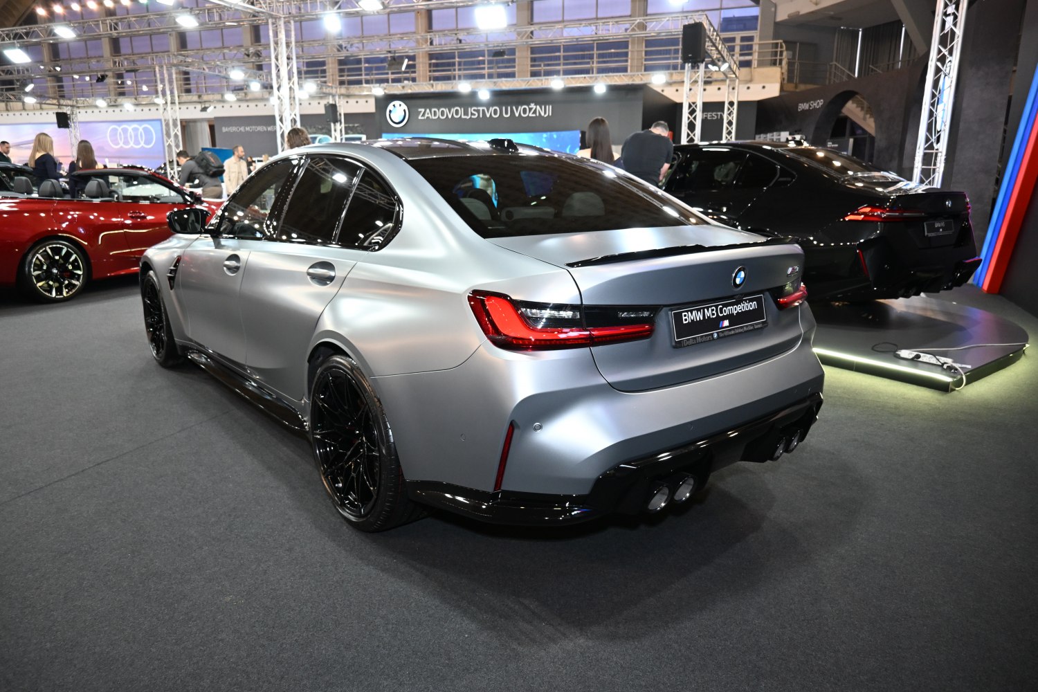 Matte silver high-performance sedan with quad exhaust and black sporty wheels