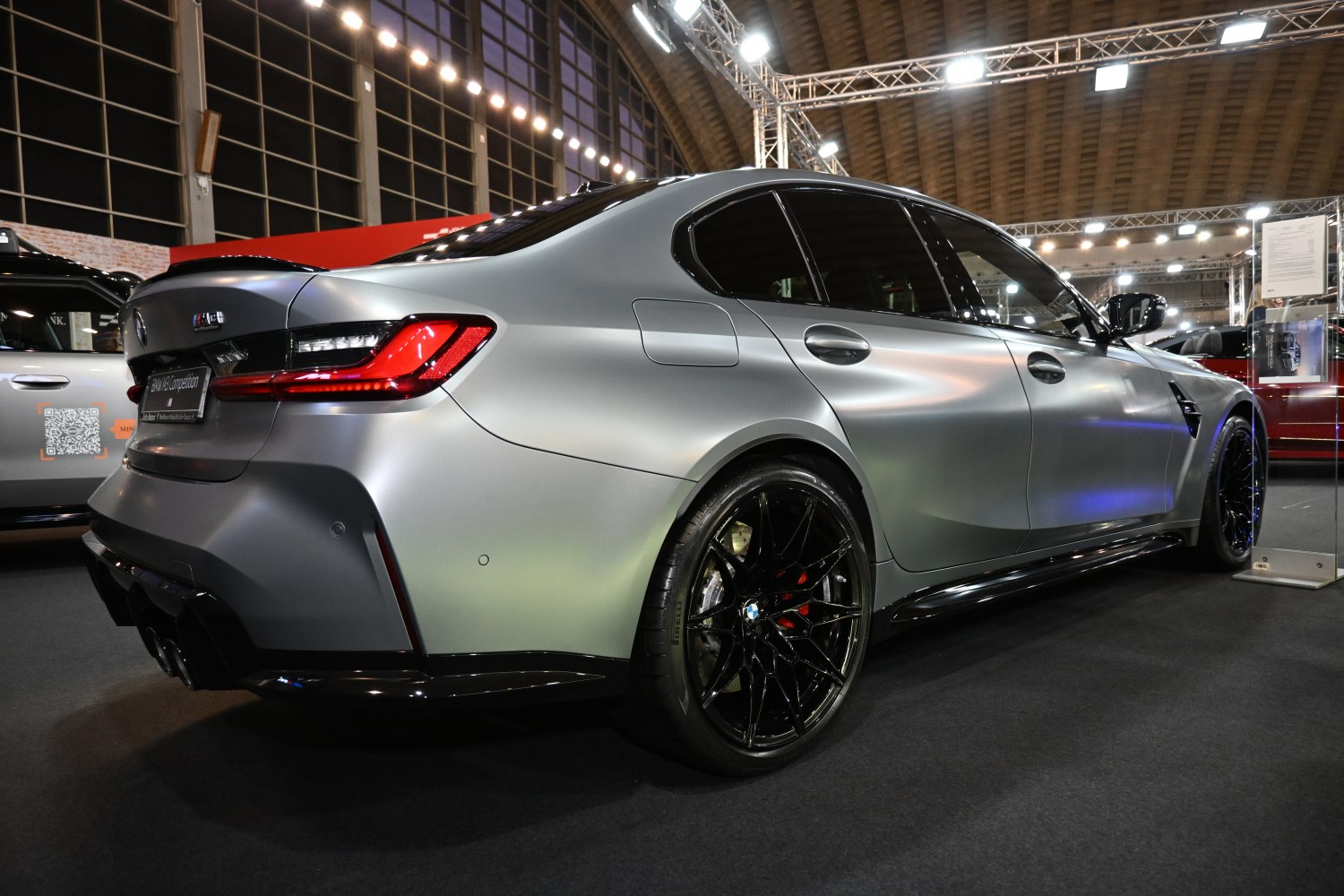 Rear and side view of a matte gray performance sedan with black multi-spoke wheels.