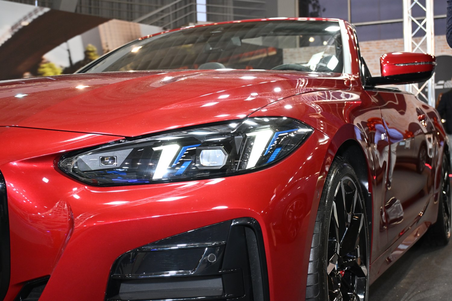 Close-up of red convertible with aggressive LED headlights and sporty front wheel.