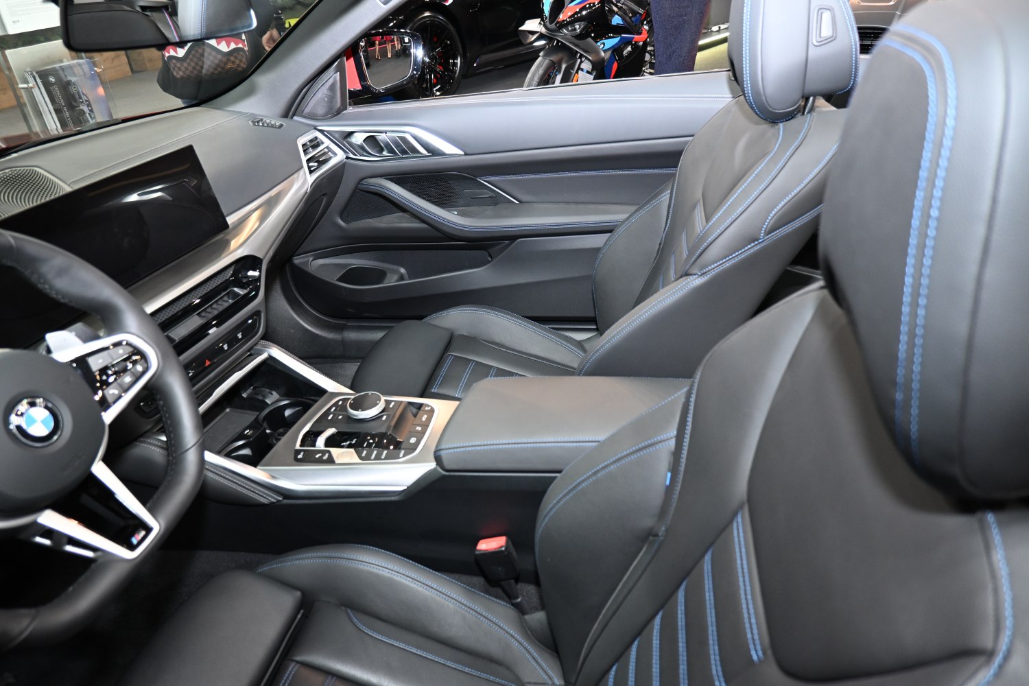 Luxury leather seats with blue stitching and advanced center console controls.