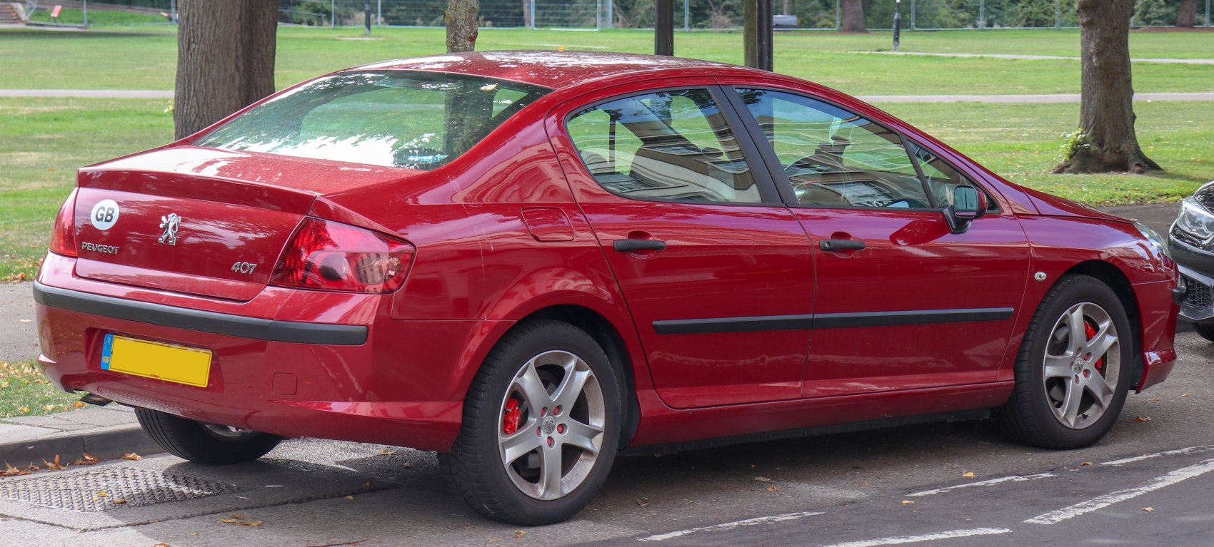 Rear and side view of a red sedan with five-spoke alloy wheels