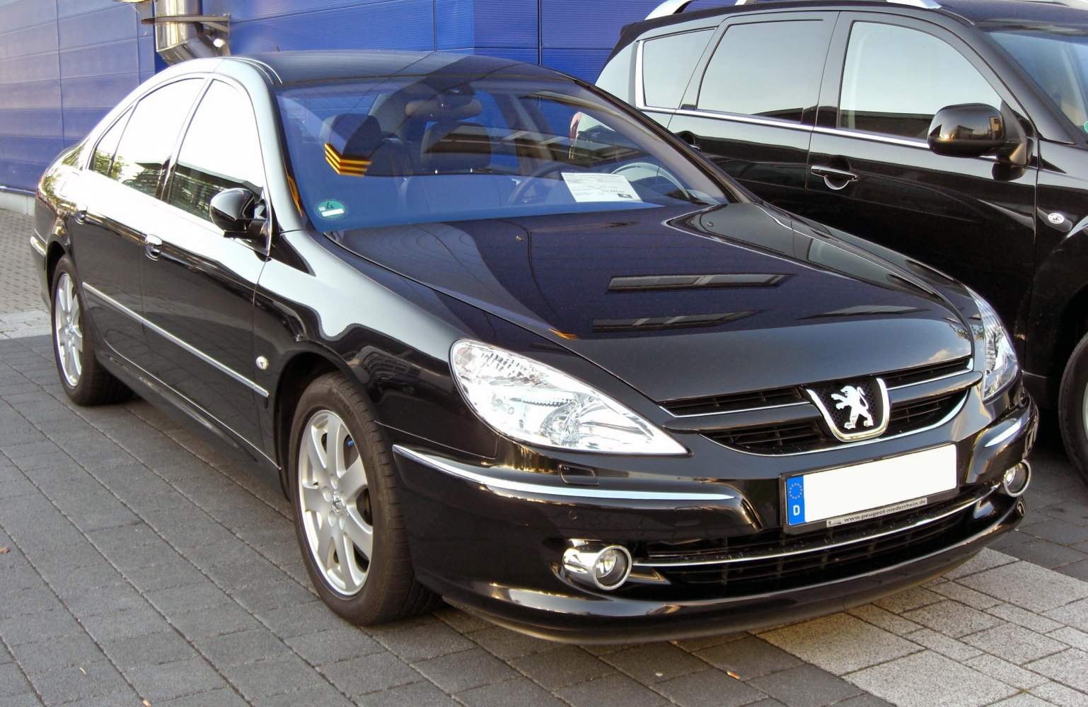 Front angled view of sleek black sedan with alloy wheels and chrome trim