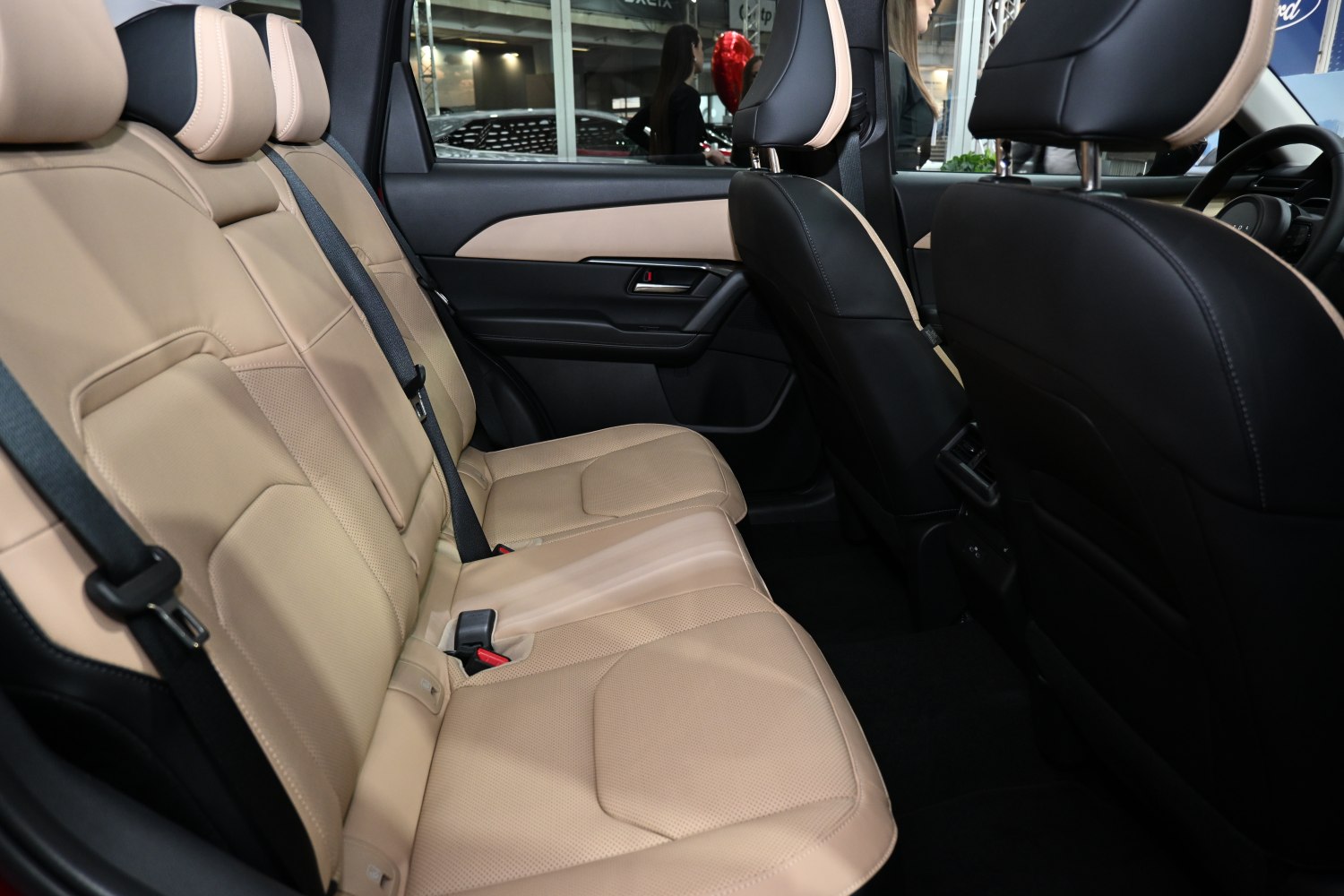 Beige leather rear seats with black interior trim and seat belts