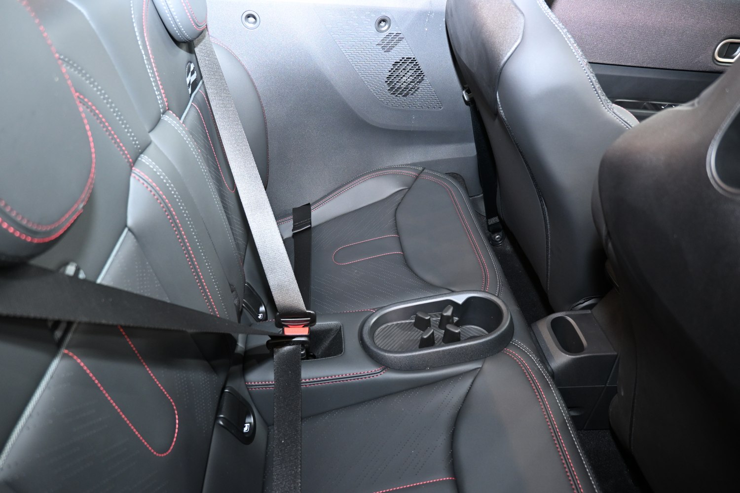 Rear seat interior with sport seats, red stitching, and cup holders