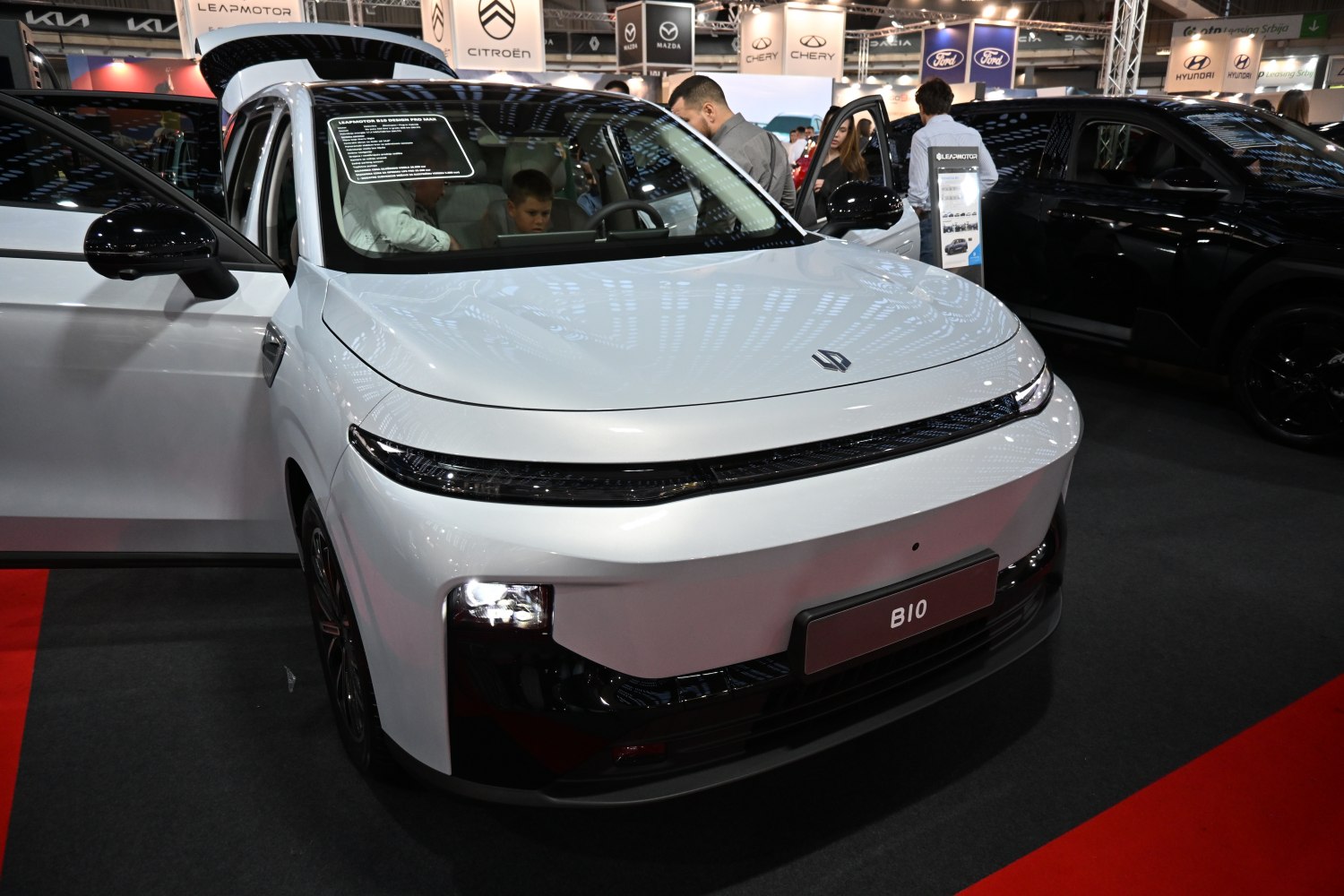 White vehicle front with sleek lights and open doors revealing interior