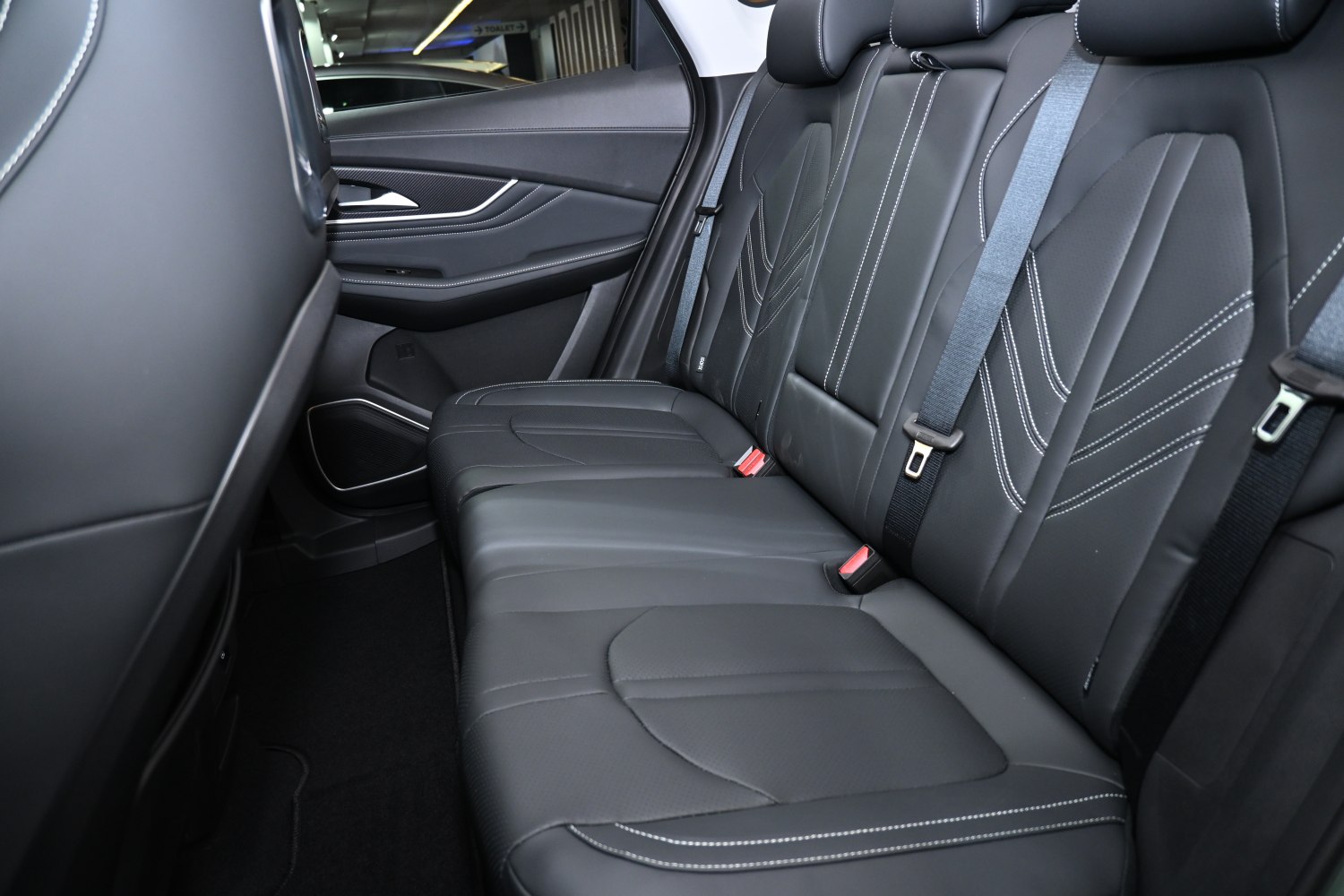 Black leather rear seats with detailed white stitching and seat belts.